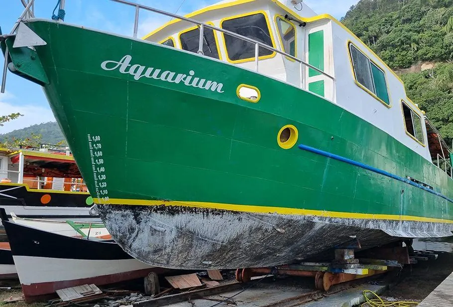 Embarcação Aquarium em obra no estaleiro, casco verde com detalhes amarelos