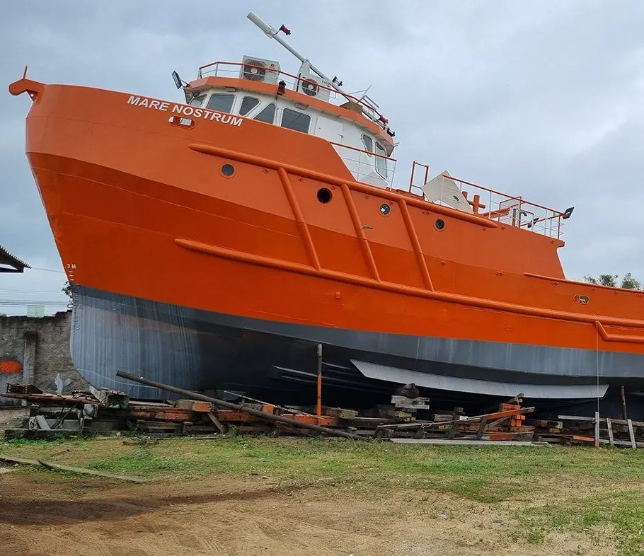 Embarcação Mare Nostrum em obra no estaleiro, casco laranja e fundo cinza recém-pintados